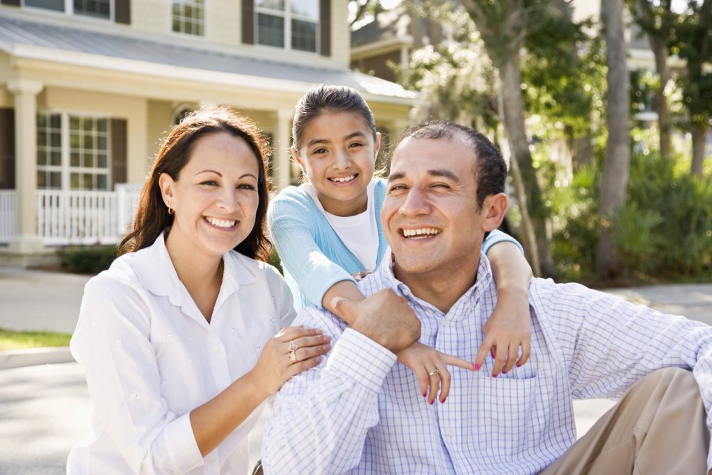 Happy family protected with no medical exam mortgage insurance in front of their home