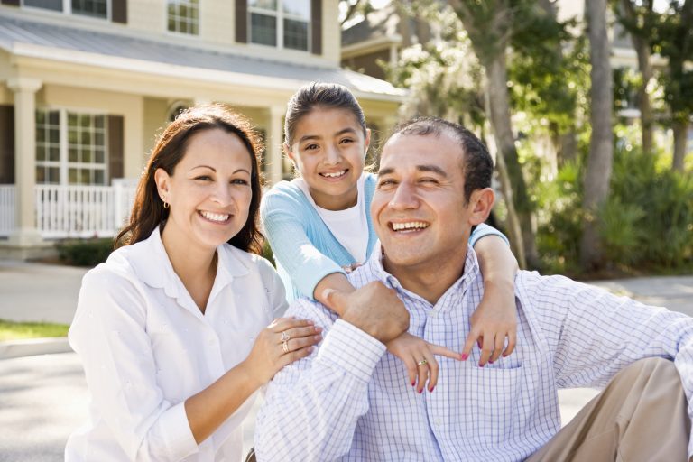 Happy family protected with no medical exam mortgage insurance in front of their home.